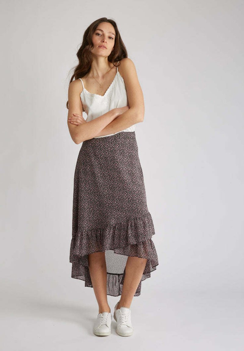 Jupe fluide asymétrique à motif floral sombre avec des détails volantés. Associée à un top en dentelle blanc et des baskets blanches. Tissu lisse et léger.