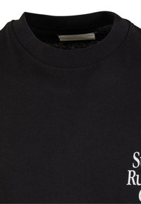 Black cotton t-shirt with a round neckline. Features white text detailing on the front. Smooth texture, simple design.
