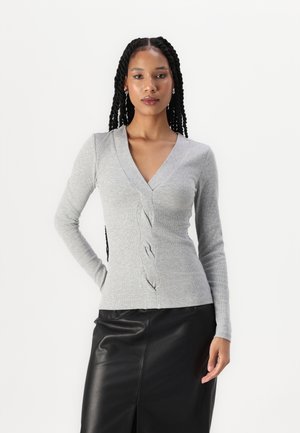 Grijze lange mouwen cardigan met een geribbeld patroon, met een V-hals en decoratieve knopen langs de voorkant, gecombineerd met een zwarte leren rok.