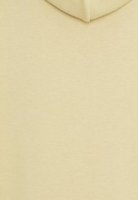 Jasnożółta bluza z kapturem o miękkiej, gładkiej fakturze i ściągaczu przy kapturze. Tkanina wydaje się przewiewna i casualowa w stylu.