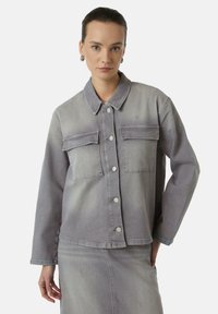 Grijze denim jacket met een kraag, twee borstzakken met kleppen en knoopsluitingen. De stof heeft een zachte, gestructureerde afwerking.