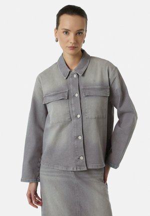 Grijze denim jacket met een kraag, twee borstzakken met kleppen en knoopsluitingen. De stof heeft een zachte, gestructureerde afwerking.