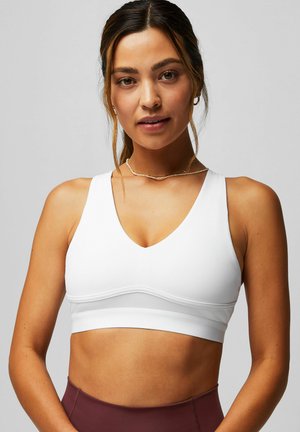 Soutien-gorge de sport blanc avec un design en V, des bretelles larges et un matériau doux. Présente une bande contrastante sous la poitrine et une texture lisse.