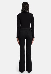 Zwarte top met lange mouwen gecombineerd met zwart hooggewijde flare jeans. De outfit heeft een gladde textuur en een minimalistisch ontwerp.