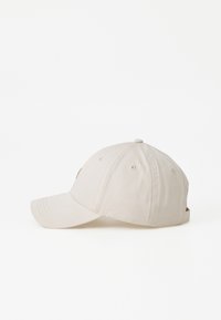 Casquette de baseball beige avec une visière courbée, en matériau textile, détails cousus et un petit logo à l'avant. Sangle ajustable à l'arrière.