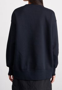 Dark navy sweatshirt with a round neckline, dropped shoulders, and ribbed cuffs. Features a soft texture and a relaxed fit.