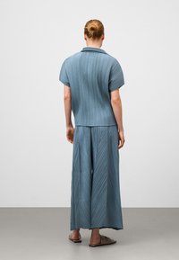 Completo plissettato blu chiaro composto da una blusa a maniche corte e pantaloni a gamba ampia, caratterizzato da un motivo a strisce verticali testurizzato.