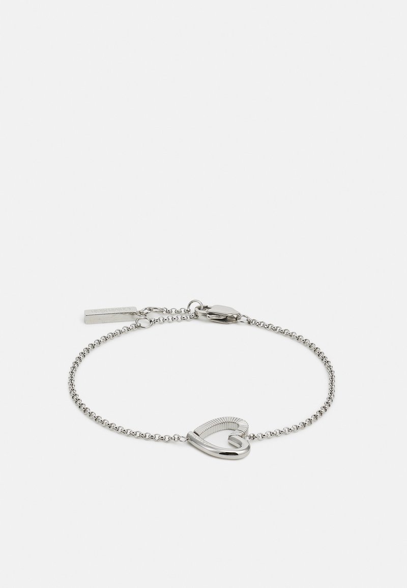 Silver chain bracelet featuring a stylized heart charm with a ribbed pattern and a lobster clasp. Smooth and metallic finish throughout.