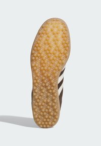 Semelle de sneaker en caoutchouc marron avec une texture en nid d'abeille. Accents blancs à rayures notables courant le long du côté. Design flexible pour une adhérence optimale.