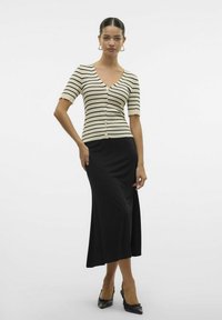 Črtasta, kratka majica s kratkimi rokavi v kremni in črni barvi, kombinirana s črno krilo do kolen s stranskim razporkom. Črne čevlje z visokimi petami dopolnjujejo videz.