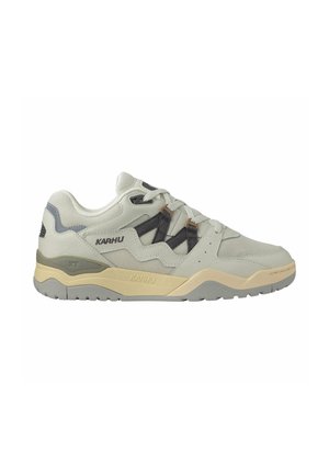 Lysegrå Karhu-sneakers med beige mellemsål, grå accenter, sorte snøreløkker og tekstureret gummiydersål, vist i sideprofil på hvid baggrund.