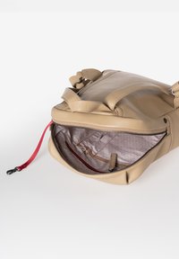 Beige leren tas met een ritssluiting, met een textuur binnenin en een rode trekker. Inclusief binnenzakken voor organisatie.