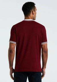 Bordeaux-kleurig T-shirt met korte mouwen, voorzien van witte gestreepte randen bij de kraag en mouwen, gemaakt van een soepele katoenstof, met een ontspannen pasvorm.