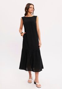 Czarna, bezrękawnikowa sukienka maxi z okrągłym dekoltem, warstwowymi dołem i bocznymi kieszeniami; wykonana z lekkiego materiału.