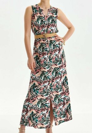 Mouwloze maxi-jurk met knopen aan de voorkant, met een tropische print van roze, groen en zwarte bladeren en dieren, gecombineerd met een beige riem en een gouden armband.