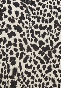 Tessuto a stampa leopardata bianco e nero con una fila verticale di cinque bottoni neri cuciti al centro.