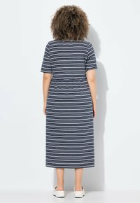 Pasiasta sukienka midi w kolorze granatowym i białym. Krótkie rękawy, elastyczna talia, prosty krój i gładki bawełniany materiał. Dobrana z białymi butami typu slip-on.