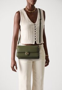 Borsa a tracolla verde in pelle con dettagli dorati, dotata di chiusura a pattina e design testurizzato. Tracolla regolabile e linee pulite.