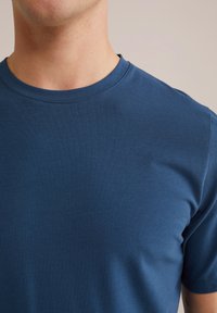 Tricou cu mânecă scurtă, de tip crewneck, fabricat din bumbac albastru moale. Are o textură netedă și un design simplu, clasic, fără modele sau accente.