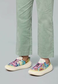 Des baskets colorées avec un design à imprimé floral, présentant des lacets roses, une semelle blanche texturée et un col rembourré léger.