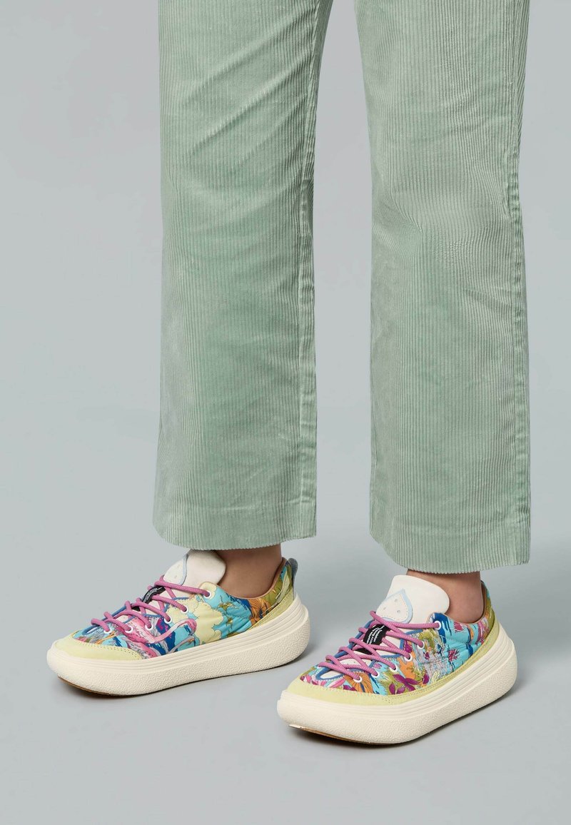 Des baskets colorées avec un design à imprimé floral, présentant des lacets roses, une semelle blanche texturée et un col rembourré léger.