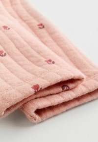 Strikket bomuldsstof i blød pink med små blomster-mønstre. Materialet har en ribbet tekstur, med foldede kanter der viser en pæn finish.