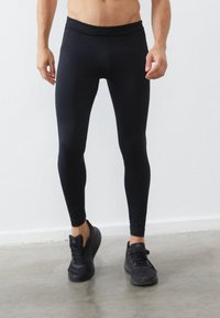 Črne atletske leggins hlače v tesnem kroju, narejene iz gladkega, elastičnega materiala, z širokim pasom in brez vidnih vzorcev.