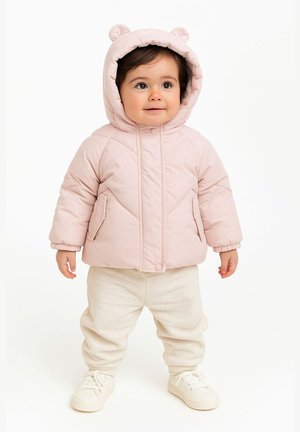 Helles rosa gesteppte Jacke mit Bärenohr-Kapuze, Fronttaschen und Reißverschluss, kombiniert mit cremefarbenen Jogginghosen und weißen Sneakern.