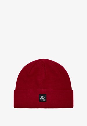 Rode gebreide muts met een omgeslagen boord, voorzien van een rechthoekig zwart label met een berglogo en het woord "PROTEST." Zachte textuur.