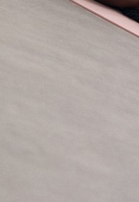 Material rosa e grigio su una superficie piana, con una texture liscia e un motivo sottile, parzialmente coperto da un altro oggetto.