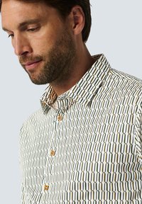 Patroon shirt met een geometrisch ontwerp in groen, beige en wit; knoopsluiting kraag; houten knopen; gladde textuur.