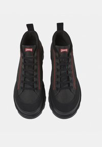 Sneakers alte nere realizzate in materiale sintetico. Le caratteristiche includono cuciture rosse, lacci neri e un logo prominente sulla linguetta.