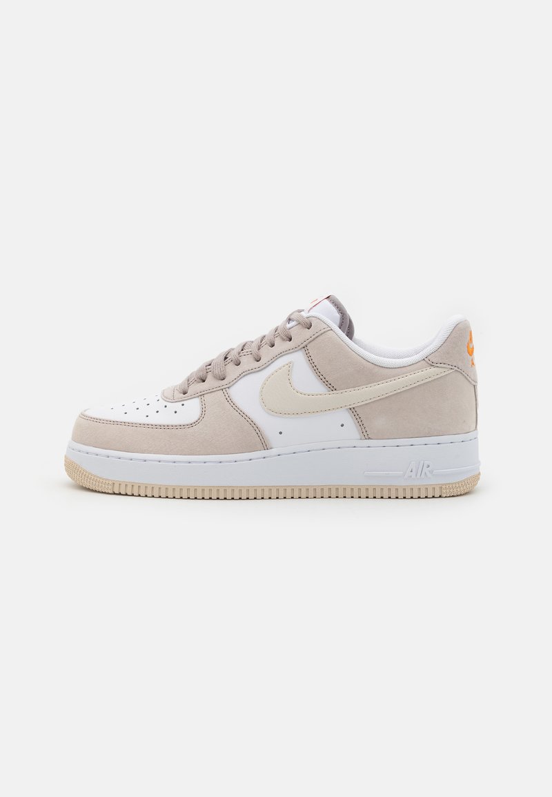 Sneakers met een bovenwerk van wit leer en beige suède accenten. Gladde, ronde neus, tonale veters, rubberen zool en een oranje logo op de hiel.