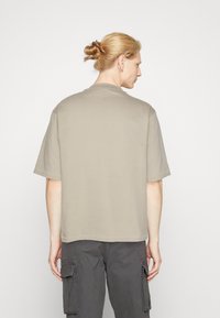 Korte mouwen unisex T-shirt in lichtbeige katoen, met een ronde hals en een ontspannen pasvorm met een rechte zoom.