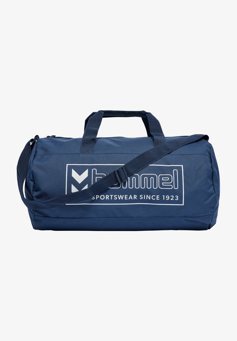 Mörkblå duffelväska med vävda handtag och justerbar axelrem. Har en stor vit logga och en texturerad tygutsida.