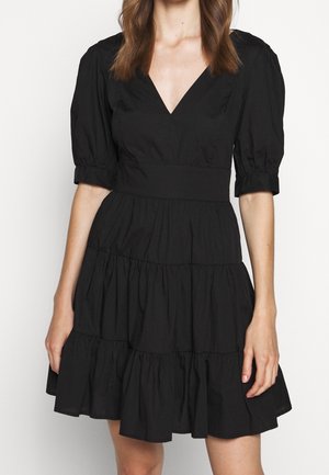 Robe noire à manches bouffantes avec un col en V, bustier structuré et ourlet à volants en couches. Fabriquée en tissu léger, avec une texture douce.