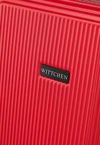 Valigia rossa con una texture a righe, dotata di una piastra con il logo nero del marchio "WITTCHEN". Materiale resistente e forma rettangolare.