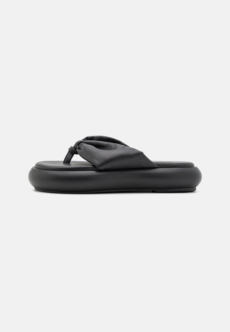 Tongs noires avec une semelle coussinée et une sangle en matériau doux nouée. Texture lisse et design épuré.