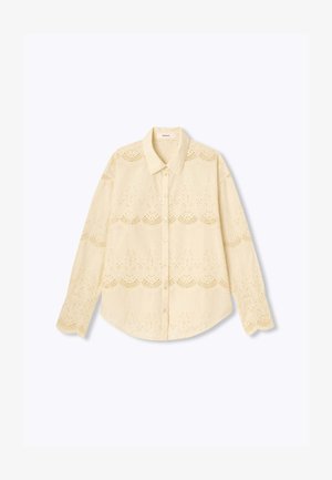 Chemise à manches longues jaune clair avec une fermeture à boutons, présentant des motifs brodés en œillets et un design de col classique.