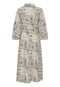Robe à manches longues avec des motifs tribaux géométriques noirs et blancs, col montant et taille cintrée, vue de dos.