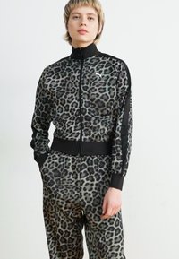 Tuta in stampa leopardata, nei toni del grigio e del nero, con giacca con zip, colletto alto e vita elastica.