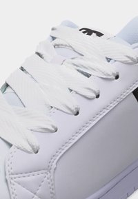 Λευκό αθλητικό παπούτσι με χοντρές λευκές κορδόνια που περνούν μέσα από πέντε μεταλλικά κουμπώματα, με λεπτομερή ραφές και μερικό μαύρο λογότυπο στη γλώσσα.