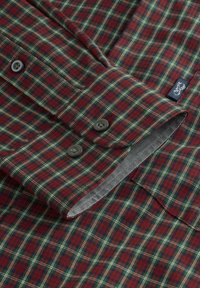 Camisa a cuadros rojos y verdes con interior gris, con cierres de botón y una pequeña etiqueta. Tejido suave con una textura lisa.