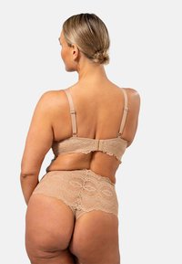 Beige lace alushõng, millel on reguleeritavad rihmad. Rinnahoidjal on nööpkinnitus; aluspükstel on pitsdetail ja läbipaistev kangas taga.