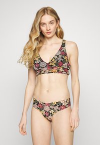 Conjunto de biquíni floral com um fundo preto e padrões coloridos de margaridas. O top tem um design de decote em V e alças largas; as partes de baixo são cuecas.