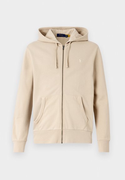 Beidzis kapucīns ar rāvējslēdzēju, izgatavots no mīksta auduma, ar regulējamu kapuci, divām priekšējām kabatām, ribotiem pneļiem un mazu logotipu uz krūšu.