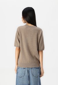 Korte mouwen bruine gebreide trui met een zachte textuur, geribde halslijn en boorden, gecombineerd met een blauwe denim rok met achterzakken.