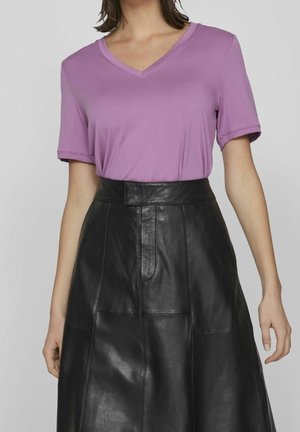 Violetti lyhythihainen V-pääntie T-paita yhdistettynä mustaan korkeavyötäröiseen nahkahameeseen, jossa on sileä pinta ja selkeät muotoilulinjat.