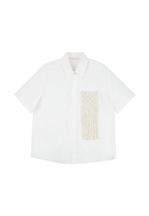 Camicia bianca a maniche corte con colletto a punta e tasca in macramé testurizzata con dettagli di frange sul lato sinistro.