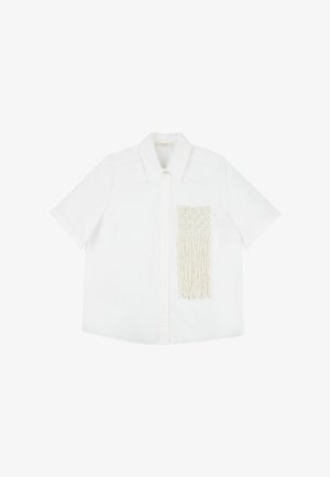 Camisa blanca de manga corta con cuello puntiagudo y un bolsillo de macramé texturizado con detalles de flecos en el lado izquierdo.